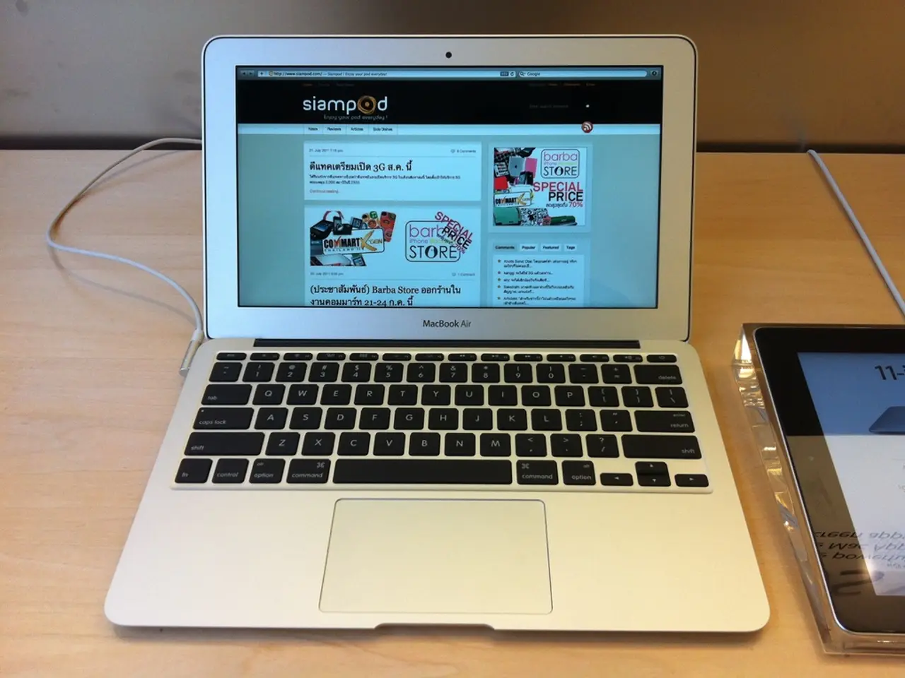 Here I can see a laptop and a device are placed on a table. On the laptop screen there is some text...