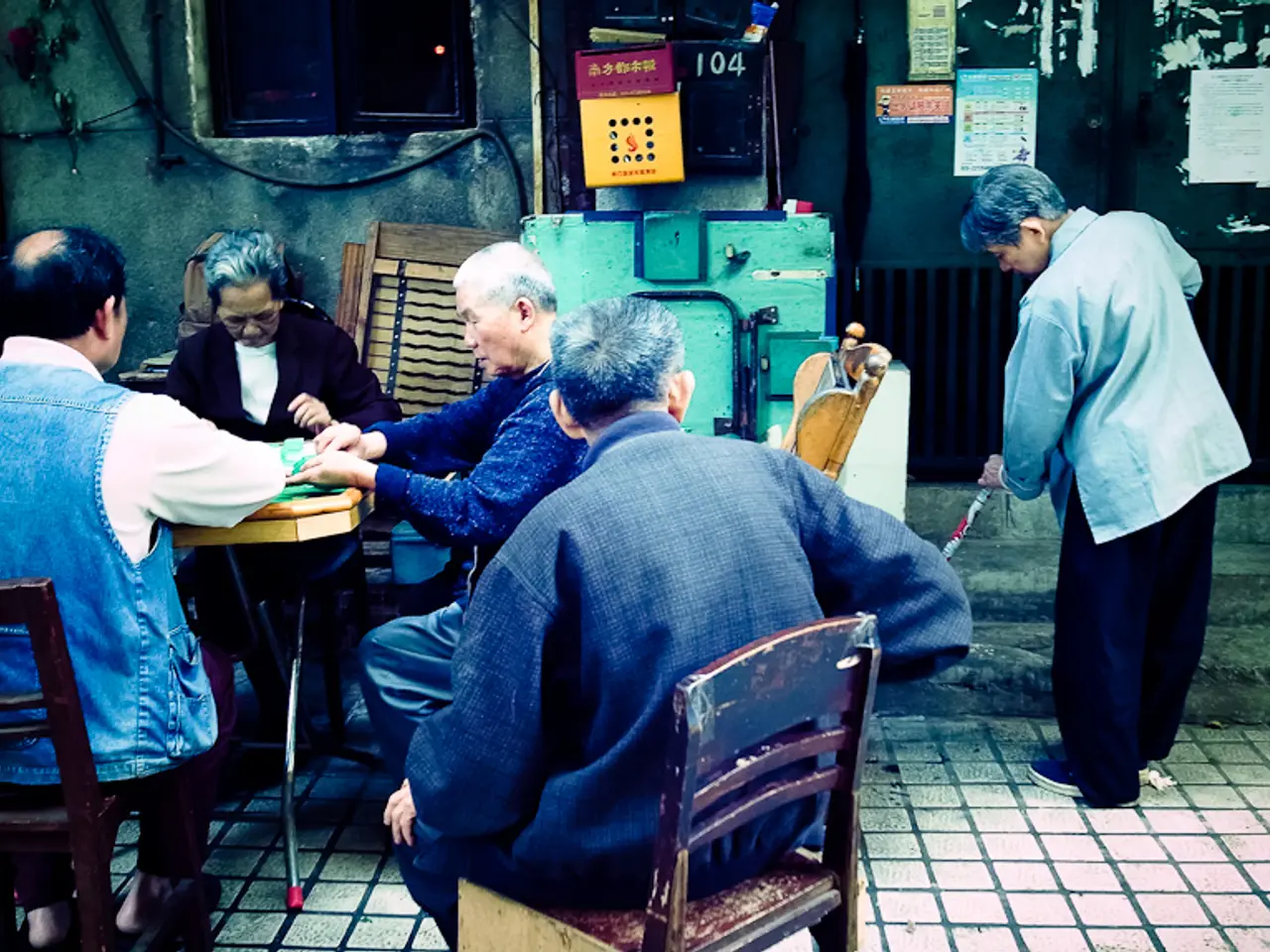 In this image there are group of people sitting on the chairs,and doing their work. Here is table...