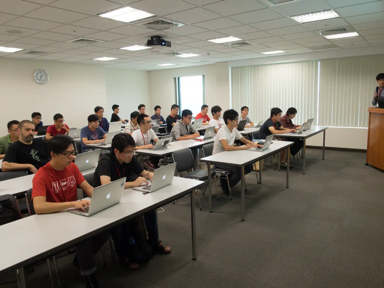 In this image there are group of people sitting and working on a laptop,the man standing here and...