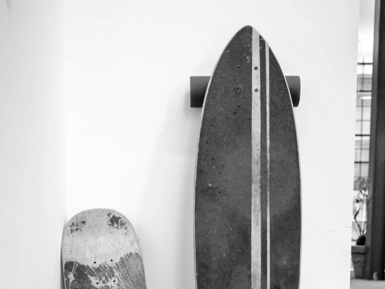 This is a black and white pic. Here we can see a two different types of skateboards on the wall and...