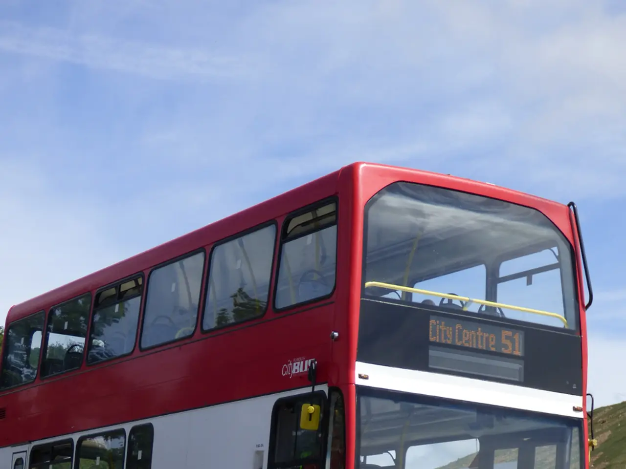 In the image we can see there is a red colour double decker bus on the road and its written "City...