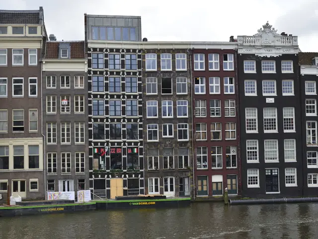 In this image we can see buildings, windows, there is an air conditioner, there are some posters,...