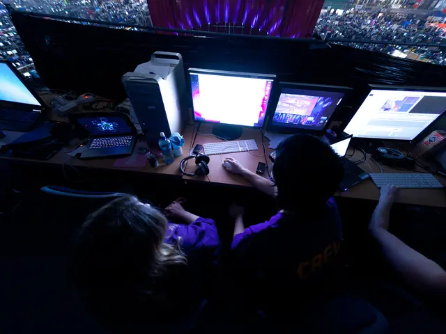 In this image we can see some people sitting on the chairs holding a mouse beside a table...