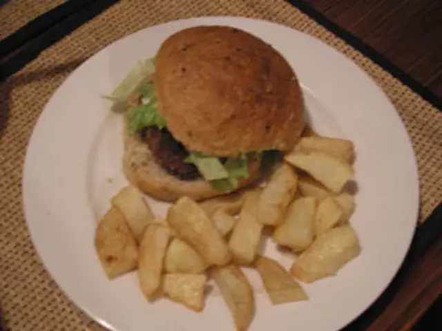 In this picture, there is a plate placed on the table. In the plate, there is a burger and french...