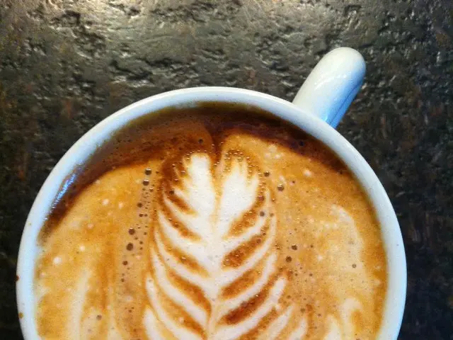 In this picture we can see a cup with coffee in it and this cup is placed on a platform.