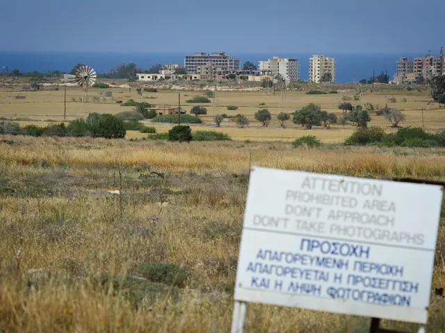 In this picture I can see few buildings and trees and a windmill on the left side of the picture...