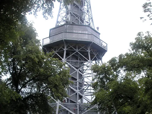 In this image in the middle, there is a tower. At the bottom there are many people, house, tents,...